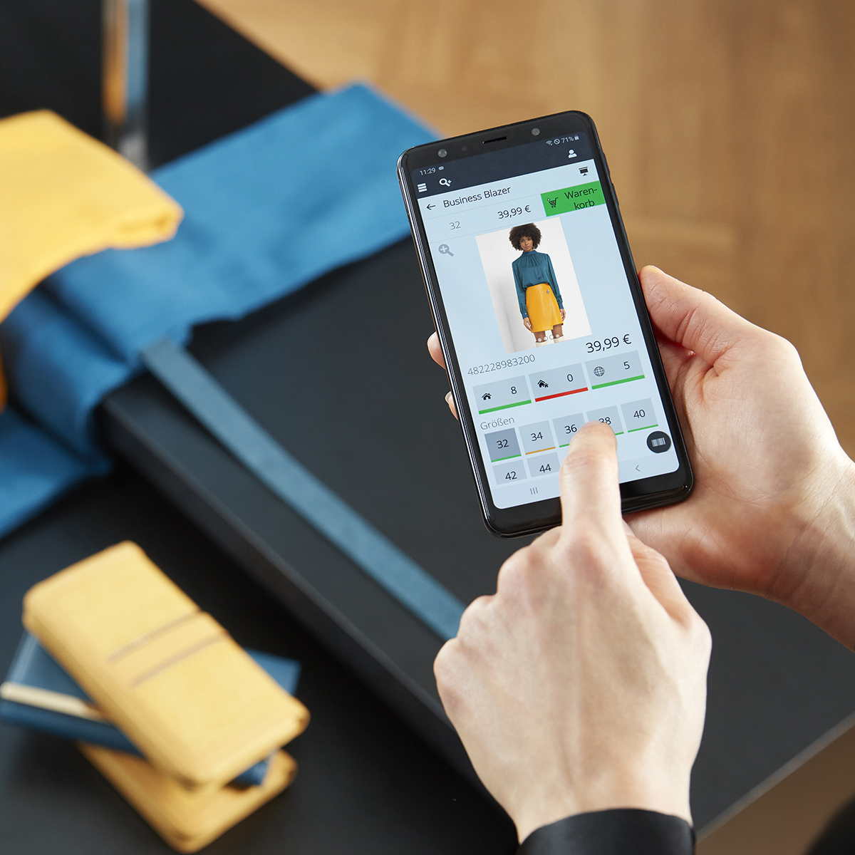 Detailansicht des InStore Assistants: Verkäuferin sieht in der Handy-App ein Outfit an und prüft die Bestände